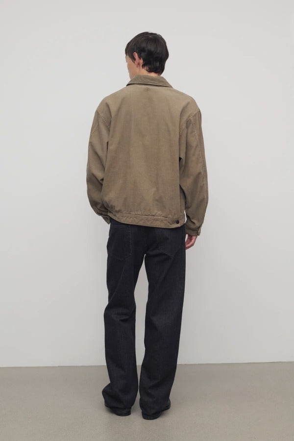 Back view of indigo rossen jean on model wearing khaki jacket and boots, against a white background.