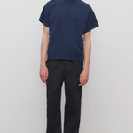 Front view of black sankuro pant on model wearing navy t-shirt, against a white background.