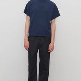 Front view of black sankuro pant on model wearing navy t-shirt, against a white background.