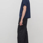 Side view of black sankuro pant on model wearing navy t-shirt and boots, against a white background.