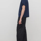 Side view of black sankuro pant on model wearing navy t-shirt and boots, against a white background.
