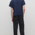 Back view of black sankuro pant on model wearing navy t-shirt and boots, against a white background.