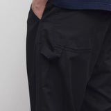 Back closeup view of black sankuro pant on model wearing navy t-shirt, against a white background.