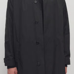 Front closeup of black tarian coat on model wearing black pants and shirt, against a white background.