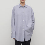 Front view of white and blue Ment shirt on model wearing black trousers, against a white background.