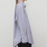Side view of white and blue Ment shirt on a model wearing black trousers, against a white background.