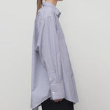 Side view of white and blue Ment shirt on a model wearing black trousers, against a white background.