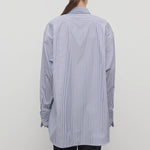 Back view of white and blue Ment shirt on model wearing black trousers, against a white background.