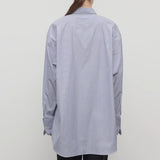 Back view of white and blue Ment shirt on model wearing black trousers, against a white background.