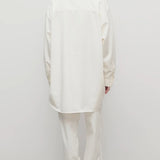 Back view of white neriah pants on model wearing white jacket and sneakers, against a white background.