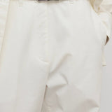 Front closeup of white neriah pants on model wearing ivory top and black belt, against a white background.