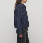 Side view of indigo ness jacket on model wearing black jeans and t-shirt, against a white background.