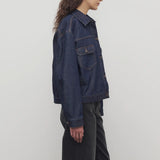 Side view of indigo ness jacket on model wearing black jeans and t-shirt, against a white background.