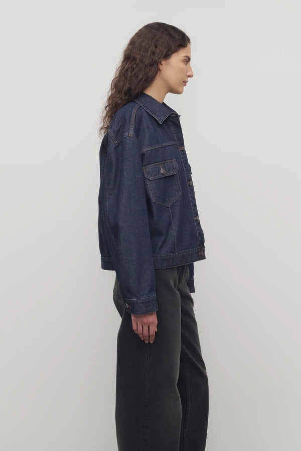Side view of indigo ness jacket on model wearing black jeans and t-shirt, against a white background.