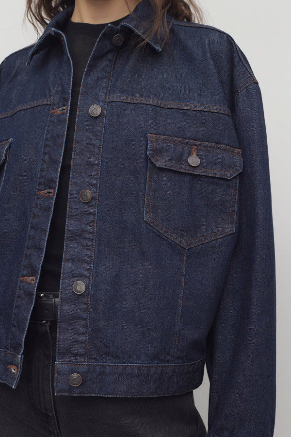 Front closeup view of indigo ness jacket on model wearing black jeans and t-shirt, against a white background.