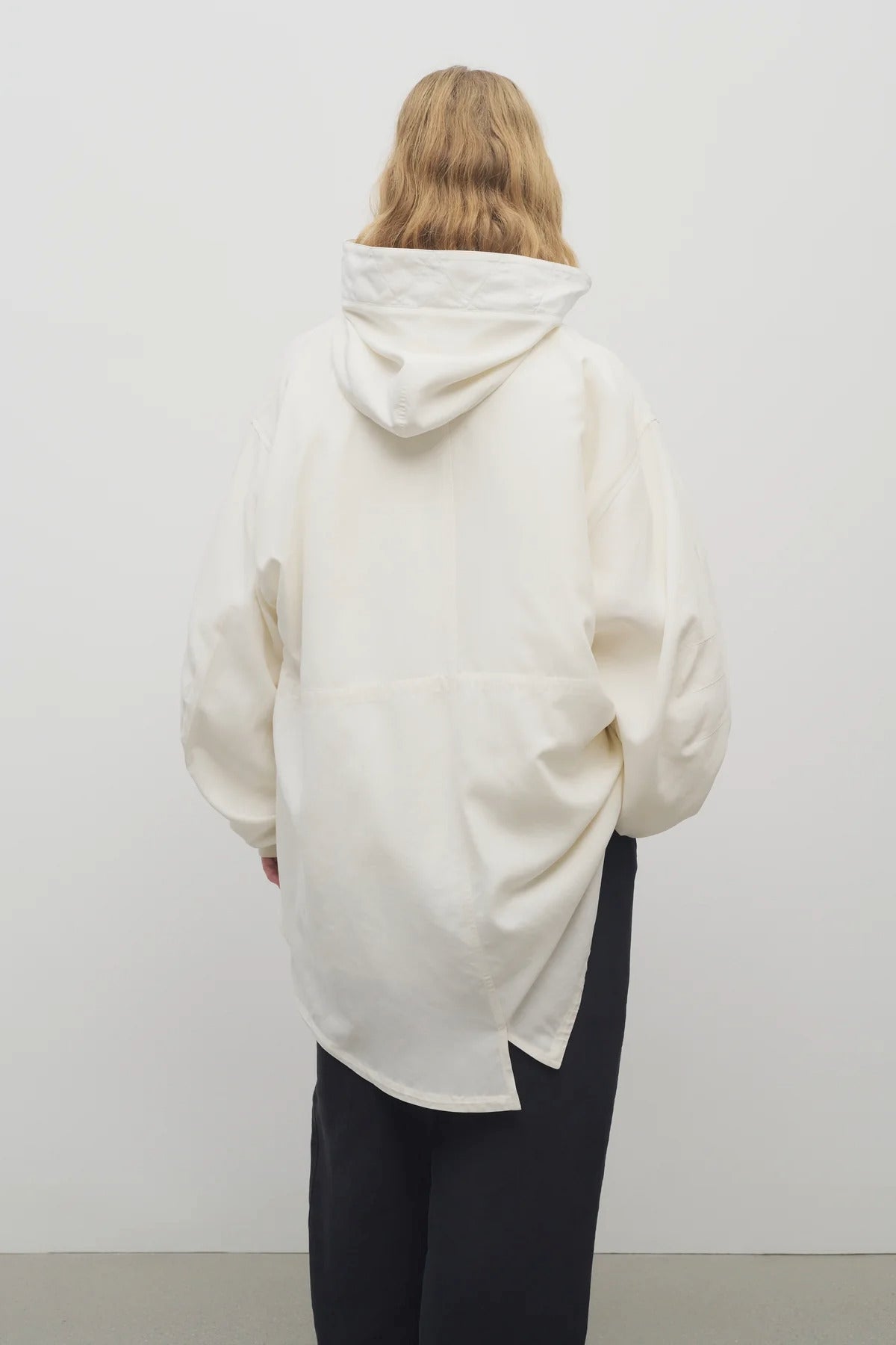 Back view of off-white Kemetina Coat on model wearing black trousers, against white background.