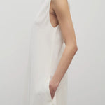Side closeup view oh off-white Nicole dress on model wearing sandals, against a white background.