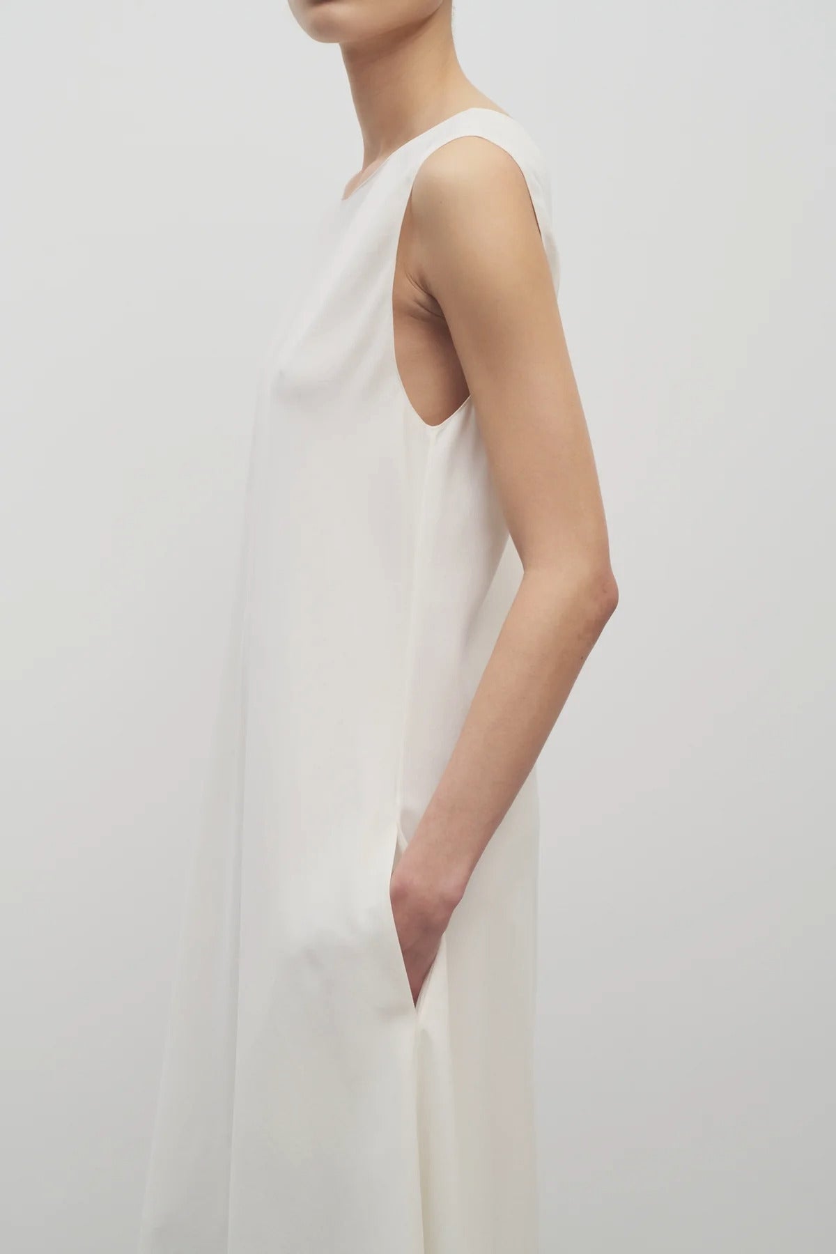 Side closeup view oh off-white Nicole dress on model wearing sandals, against a white background.