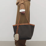 Front view of brown park tote three canvas on model wearing camel pants, sweater and boots, against a white background.