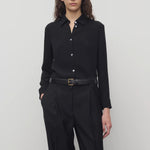 Front view of black petra shirt on model wearing black trousers, against a white background.