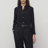 Front view of black petra shirt on model wearing black trousers, against a white background.