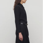 Side view of black petra shirt on model wearing black trousers, against a white background.