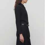 Side view of black petra shirt on model wearing black trousers, against a white background.