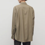 Back view of military beige pino shirt on model wearing grey pants, against a white background.