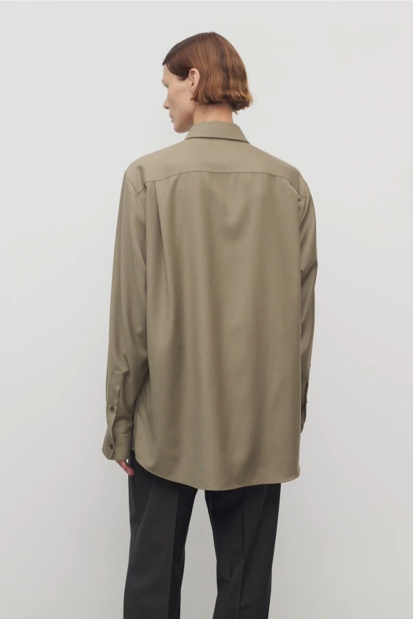 Back view of military beige pino shirt on model wearing grey pants, against a white background.