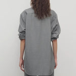 Back view of grey pino shirt on model wearing grey pants, against a white background.