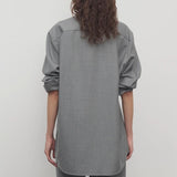 Back view of grey pino shirt on model wearing grey pants, against a white background.