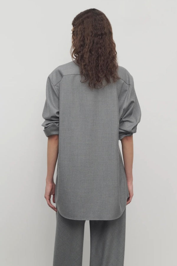 Back view of grey pino shirt on model wearing grey pants, against a white background.