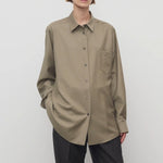 Front view of military beige pino shirt on model wearing grey pants, against a white background.