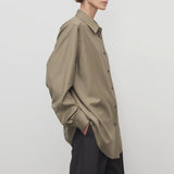 Side view of military beige pino shirt on model wearing grey pants, against a white background.