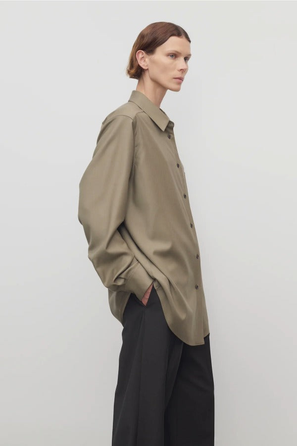 Side view of military beige pino shirt on model wearing grey pants, against a white background.