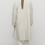 Back view of snow pluma coat on model wearing white pants and sneakers, against a white background.