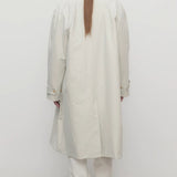 Back view of snow pluma coat on model wearing white pants and sneakers, against a white background.