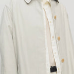 Front closeup view of snow pluma coat on model wearing white top and pants, against a white background.