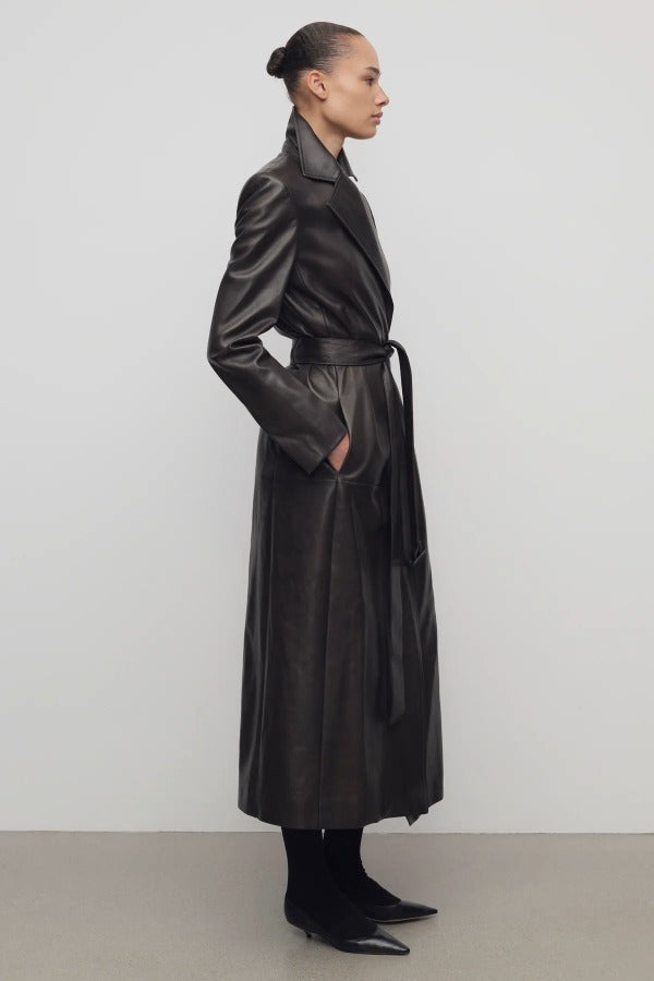 Side view of coffee raisa coat on model wearing low heels, against a white background.