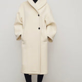 Front view of ivory regino coat on model wearing low heels, against a white background,