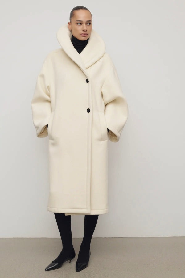 Front view of ivory regino coat on model wearing low heels, against a white background,