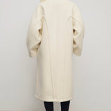 Back view of ivory regino coat on model wearing low heels, against a white background.