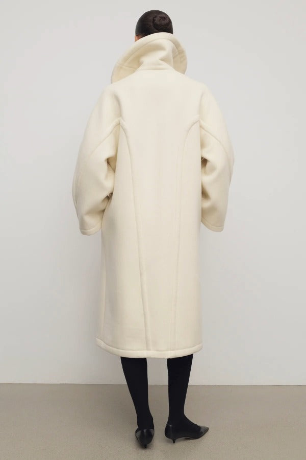 Back view of ivory regino coat on model wearing low heels, against a white background.