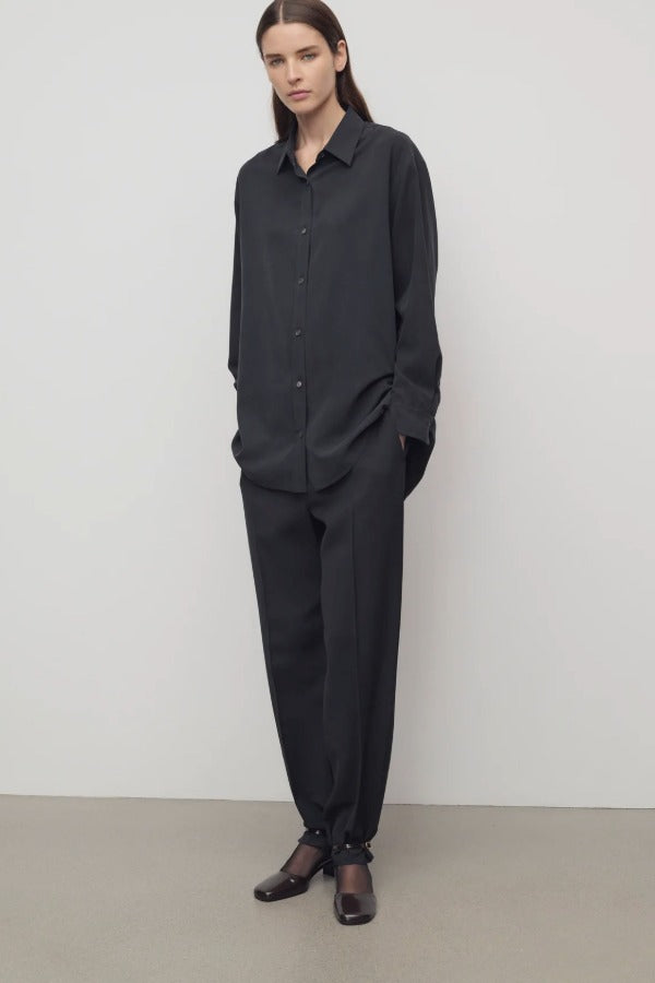 Front view of black relian pant on model wearing black shirt and heels, against a white background.