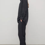 Side view of black relian pant on. model wearing black shirt and heels, against a white background. 