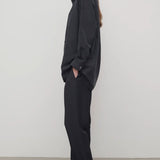 Side view of black relian pant on. model wearing black shirt and heels, against a white background. 