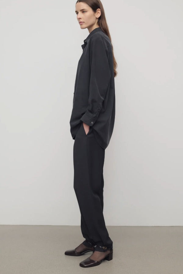 Side view of black relian pant on. model wearing black shirt and heels, against a white background. 