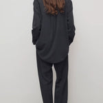 Back view of black relian pant on model wearing black shirt and heels, against a white background.