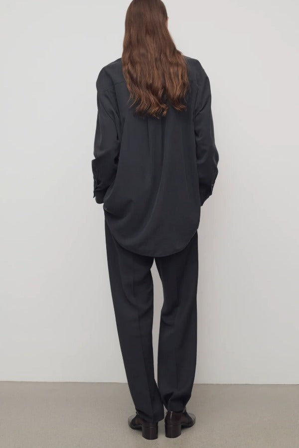 Back view of black relian pant on model wearing black shirt and heels, against a white background.