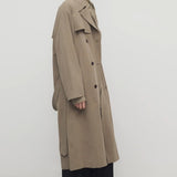 Side view of biege grey rhydian coat on model wearing black pants, against a white background.